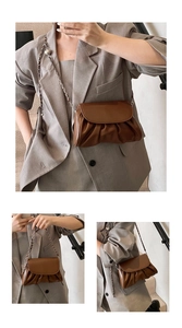 Detail of a brown pleated cloud bag featuring glossy leather and a silver metal chain strap