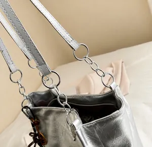 Close-up of metallic silver tote bag texture with chain strap and burgundy inner lining