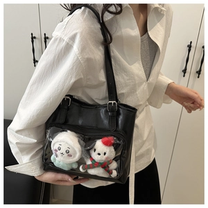 Close-up of the black tote bag featuring a transparent display window and plush charms