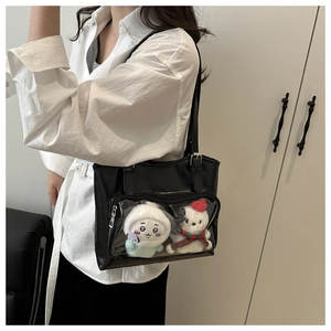 Detail of clear front pocket on black tote bag showcasing plush toys and shoulder strap