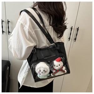 Detail of black Ita bag with transparent PVC window showing plush dolls and silver buckle