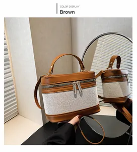 Détail d'un sac seau en cuir marron et tissu tressé beige avec double zip et métal doré