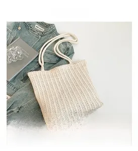 Detailed vertical stripe texture and thick cotton rope handles of a beige straw tote bag