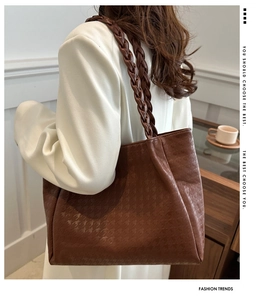 Detail of dark brown tote with houndstooth texture and braided leather handles