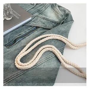 Detail of a woven cotton shoulder strap in cream white on a denim jacket background
