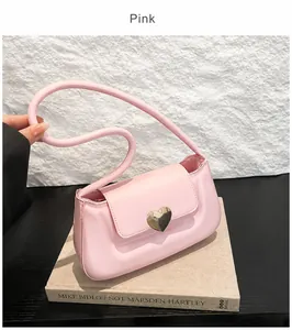 Dettaglio della borsa sottobraccio rosa con una fibbia a cuore in metallo dorato