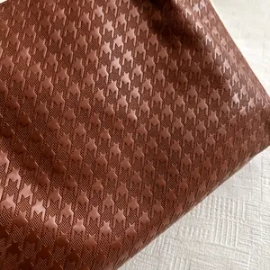 Macro shot of brown leather bag featuring sophisticated embossed houndstooth texture detail