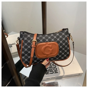 Detail of G logo embossing on canvas bag with geometric pattern and brown leather trim