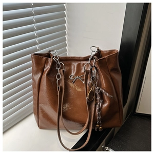 Close-up of vintage brown oil wax leather tote bag with silver bow and chain strap