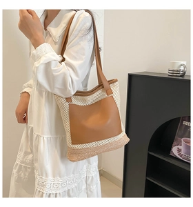 Detail view of woven shoulder tote bag with brown leather pocket and handle