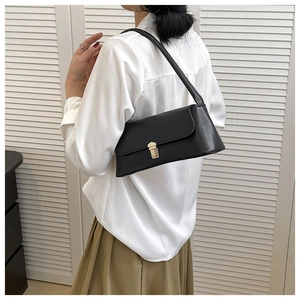 Detail of black baguette shoulder bag with gold metal buckle on minimalist background