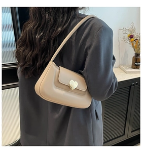 Borsa baguette beige indossata a spalla con fibbia dorata a cuore e stile chic