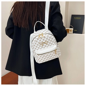 Detailed view of mini backpack featuring vintage pattern and golden bow decoration