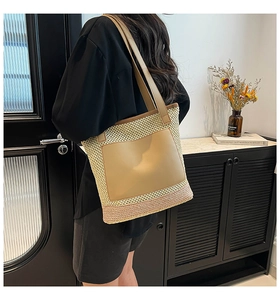 Detail of hand-woven straw tote bag with premium leather shoulder straps and front pocket