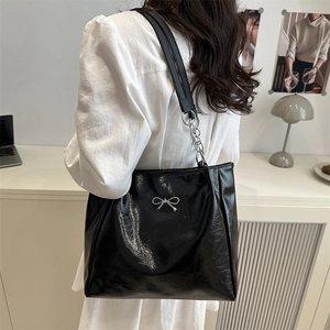 Elegant black patent leather tote bag with silver bow detail and metal chain strap