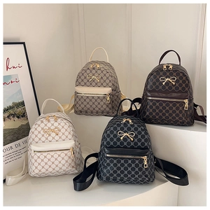 Detail of four mini faux leather backpacks in white, grey, brown, and black with bow details