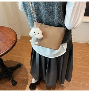 Detail showing khaki bucket bag with cute cloud plush charm and metallic shoulder strap