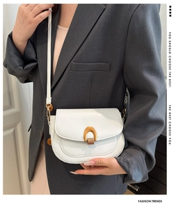 Detail of white leather saddle bag with gold horseshoe buckle and magnetic closure