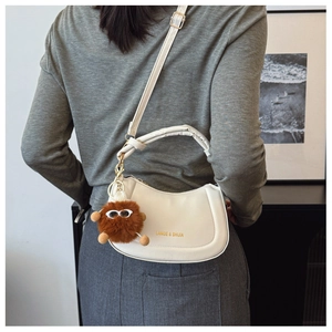 Détail du sac croissant en cuir PU blanc avec breloque peluche et logo doré