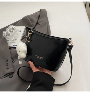 Detail of black leather handbag with gold lettering and white cloud plush charm