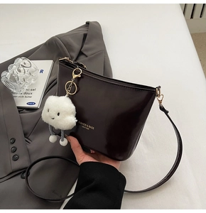Detail of dark brown leather bucket bag with gold lettering and white cloud charm