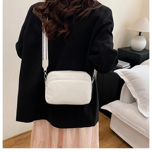 Detail of white lychee texture crossbody bag with stylish black and white striped strap