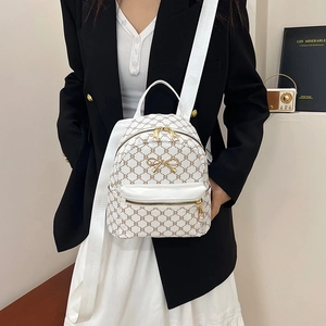 Retro white mini backpack with vintage C-pattern and gold bow accent on female model