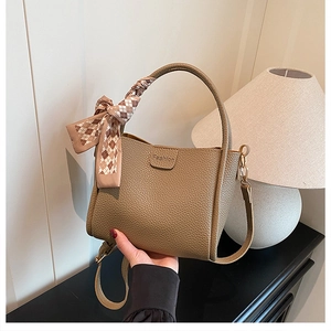 Close-up of khaki leather bucket bag with fashion embossing and silk scarf handle