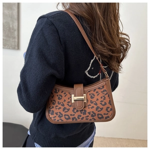 Détail du sac léopard vintage avec boucle dorée sur fond de tricot bleu marine