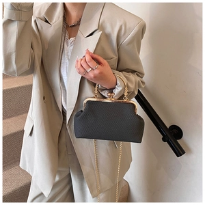 Détails d'un sac bandoulière tissé noir avec fermoir doré et poignée ronde