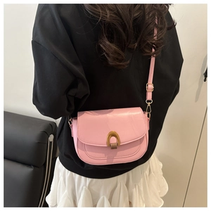 Detailed back view of pink leather saddle crossbody bag on model with gold buckle detail