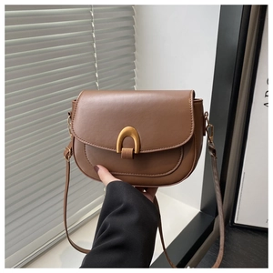 Detail of brown PU leather saddle bag with distinctive gold U-shaped metal buckle