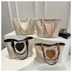 Close-up of heart-shaped woven tote bags in beige, pink, black and brown straw colors