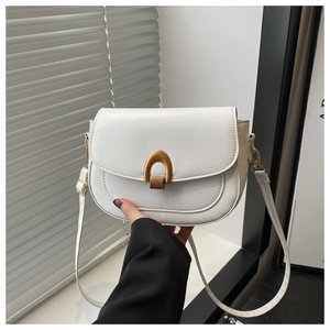 Detail of white leather saddle bag showing elegant gold U-shaped metal buckle and texture