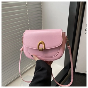 Detail of light pink saddle bag with golden horseshoe buckle and sleek leather texture