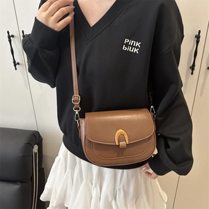 Brown leather saddle bag for women featuring a stylish gold U-shaped metal buckle