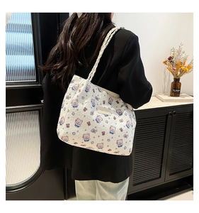 Detail of white quilted tote bag featuring cute cartoon bear prints and braided rope handles