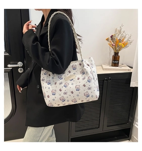 Detail of white quilted tote bag with colorful cartoon bears and woven shoulder strap