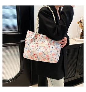 Detail of floral tote bag with textured leather and beige woven braided shoulder straps