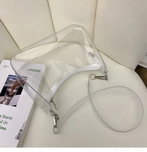 Détail d'un sac demi-lune transparent en PVC avec fermeture éclair blanche et crochets