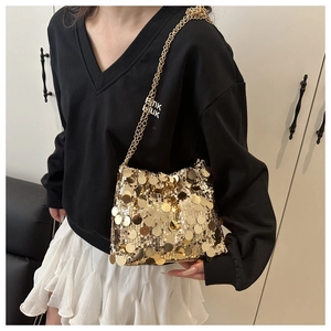Close-up of golden sequin shoulder bag with metallic chain strap worn by a model