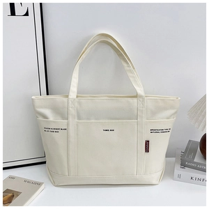 Detail view of large cream canvas tote bag with functional pockets and side label