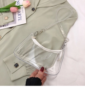 Détail du sac à bandoulière en PVC transparent montrant la fermeture éclair et les boucles en métal