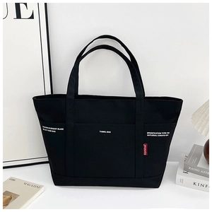 Detail of black canvas tote bag showing dual handles and functional front pockets