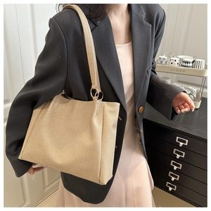 Detail of minimalist beige tote bag featuring golden metal rings and textured fabric material