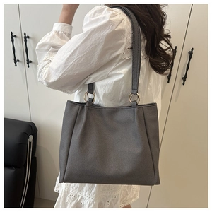 Detail of grey tote bag showing textured fabric and golden ring metal strap connectors