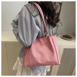 Detail of pink canvas tote bag with gold ring handle connectors on model back