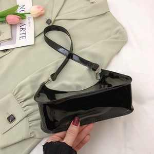 Sac en gelée PVC noir brillant au design ondulé sur une chemise vert clair et un magazine