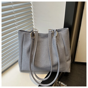 Detailed macro view of the textured blue-grey fabric and golden metal buckle of the tote bag