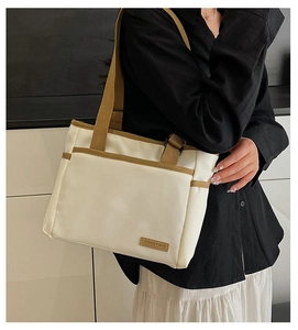 Detail of minimalist off-white canvas tote with brown straps and leather fashion label